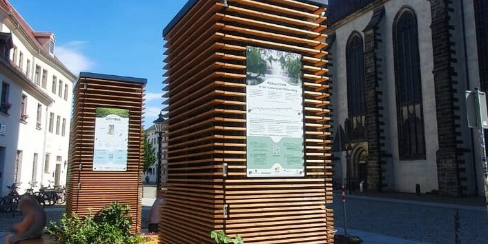 Das Bild zeigt zwei CityTrees inklusive bepflanzten Hexagonen in der historischen Altstadt der Lutherstadt Wittenberg.