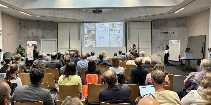 Das Bild zeigt eine Präsentation vor einem Plenum im Rahmen der Abschlussveranstaltung des Förderprogramms in Stuttgart.