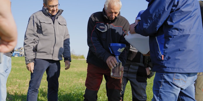 Das Bild zeigt Landwirte und einen Mitarbeiter des AELF auf einem Feld. Gemeinsam werden wasserspeichernde Bewirtschaftungsweisen und deren positive Auswirkungen auf Acker und Boden vorgeführt und besprochen.