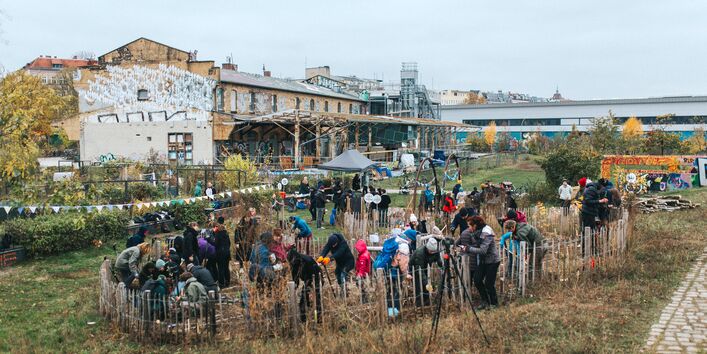 Pflanzaktion im Stadtgarten im Herbst. Im Vordergrund Menschen, die junge Bäume pflanzen, im Hintergrund das ZK/U-Gebäude.