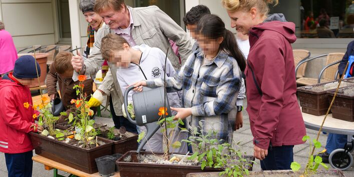 Eine Schulklasse kommt und bepflanz die Balkonkästen eines Seniorenzentrums