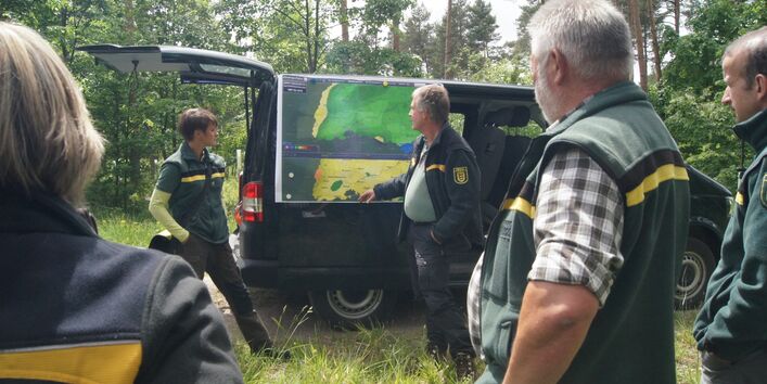 Forstmitarbeiter betrachten eine Karte im Freien.