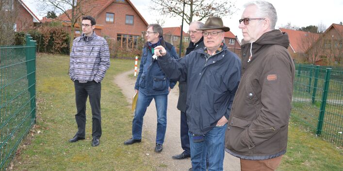 5 Personen stehen in einem Wohngebiet, eine Person erklärt etwas