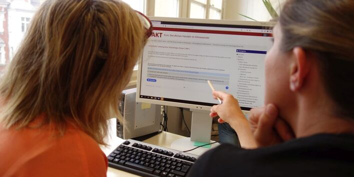 Zwei Personen schauen sich auf einem Computerbildschirm die Online-Tools des Projekts an.