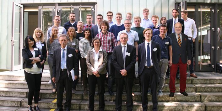 Eine Gruppe von Personen steht auf einer Treppe vor einem Gebäude.