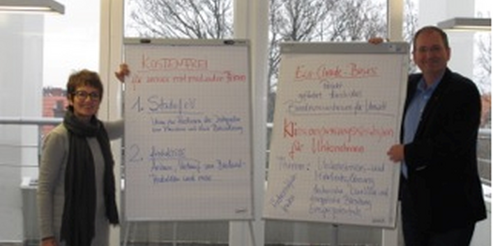 Zwei Personen stehen neben Flipcharts und präsentieren ihre erarbeiteten Ergebnisse