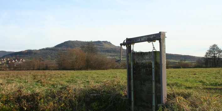 Mittig im Bild steht eine Kurbelschütz (Regulierungsvorrichtung mit Kurbel). Die senkrechte Platte, die den Graben absperren würde, ist hochgekurbelt.