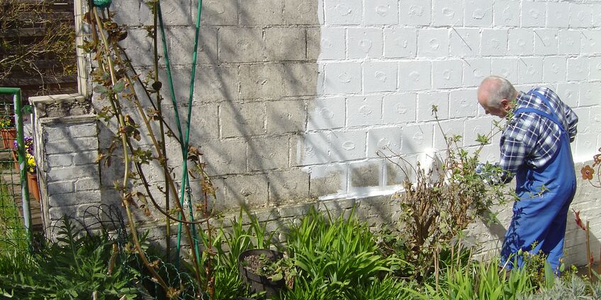 Ein Mann streicht eine Wand mit Schutzmitteln