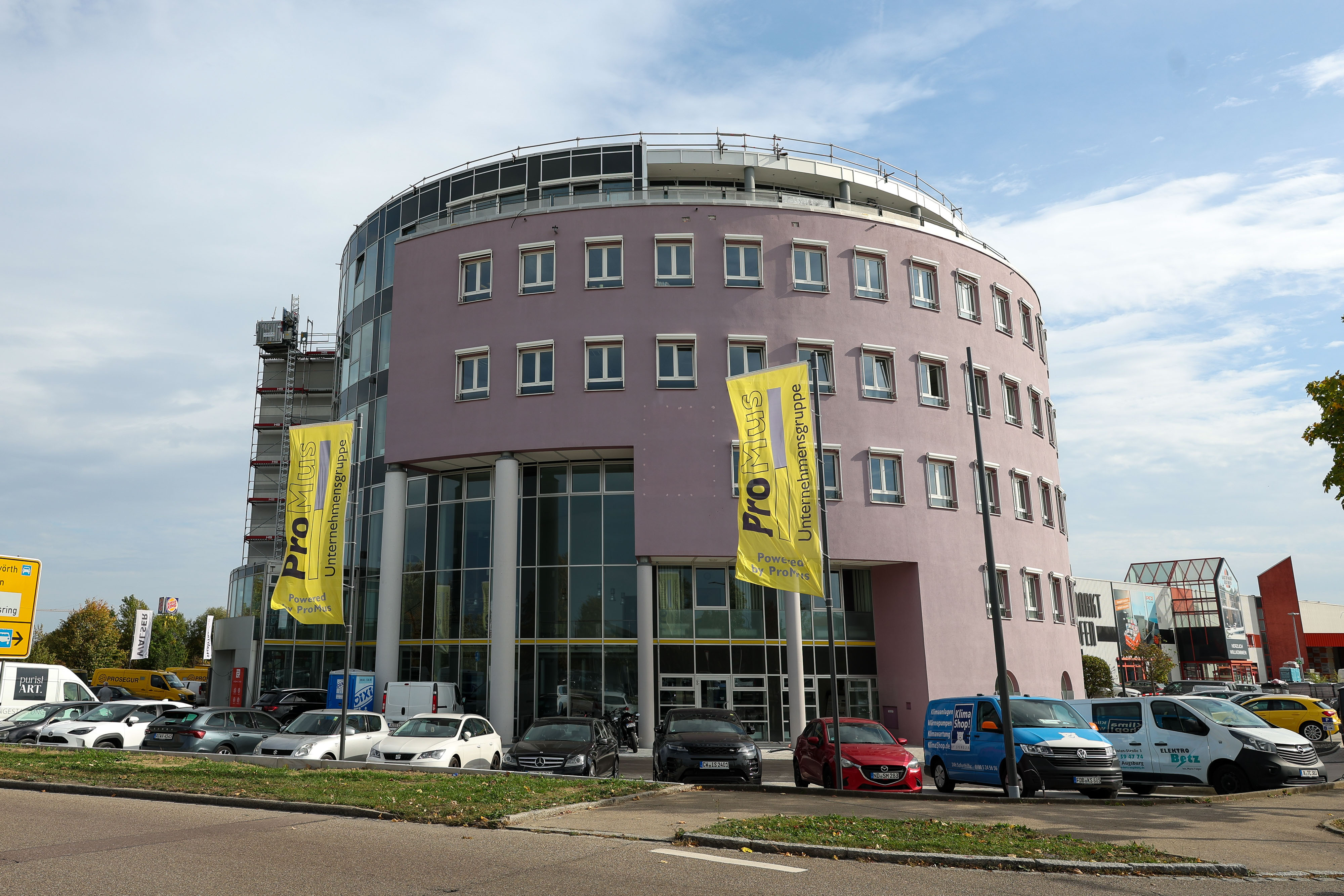 Das sechsstöckige Bürogebäude Sternodrom mit rundem Grundriss von außen. Vor dem Gebäude wehen Fahnen.