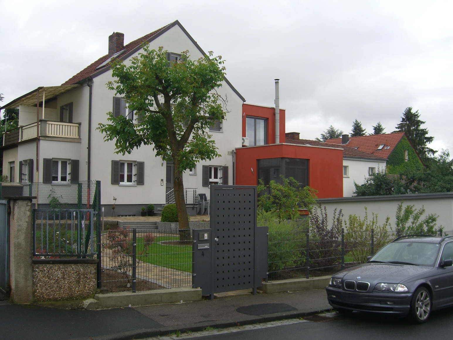 Die Ansicht eines Einfamilienhauses durch den Garten.