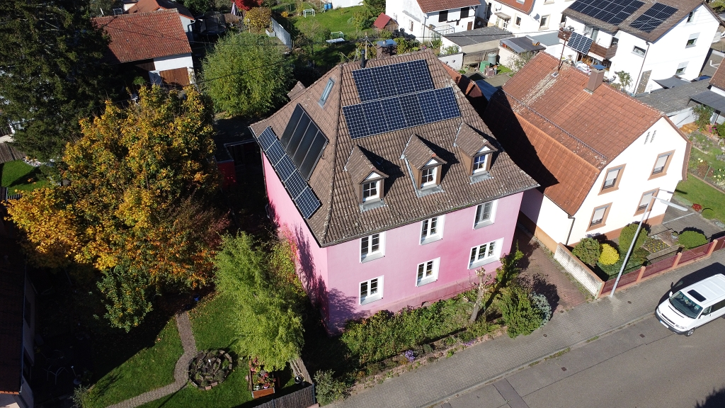 Ein rosarotes Wohnhaus von oben.