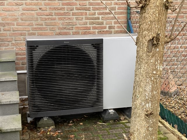 Die Außeneinheit einer Wärmepumpe an einer Hausfassade.