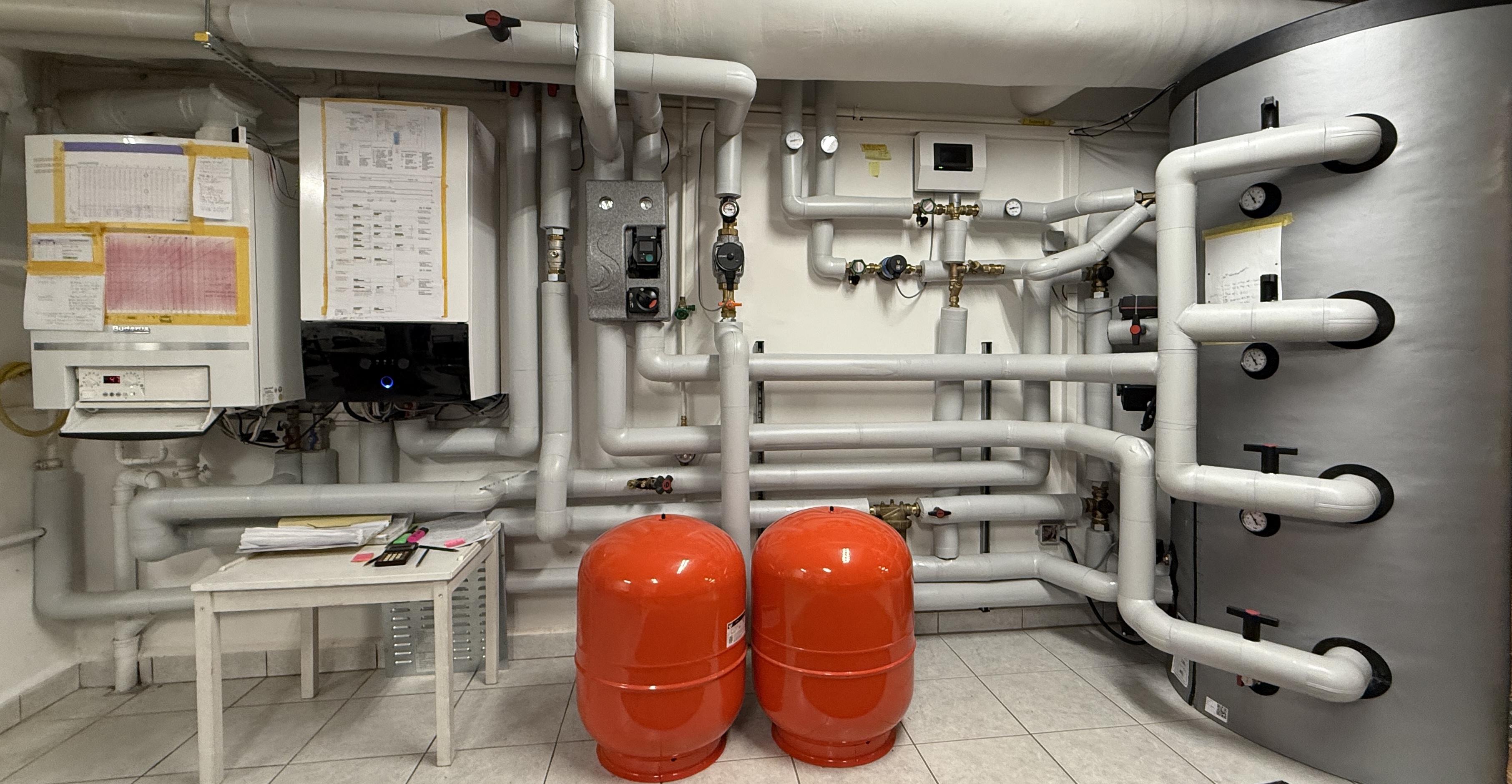 Die Heizungsanlage im Keller mit Wand-Heizkessel, Innengerät der Wärmepumpe, Pufferspeicher und isolierten Rohrleitungen