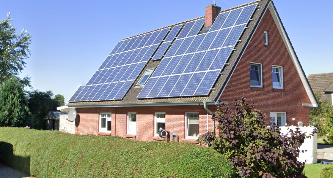 Ein geklinkertes Haus mit Photovoltaik auf dem Dach.